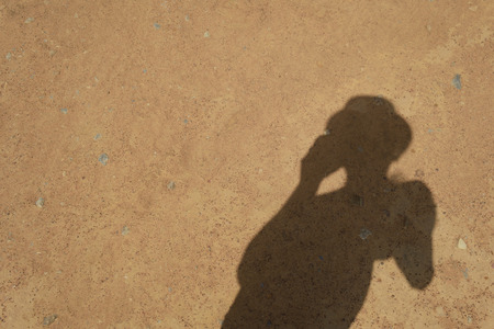 The shadow of a man standing and phone on the ground.の写真素材