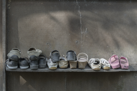Dirty old shoes on shelf of plywood wall.の写真素材