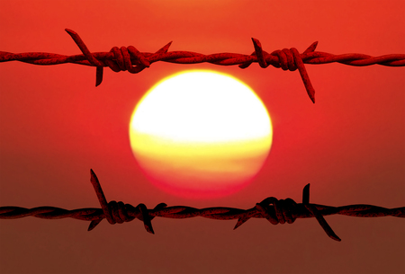 Silhouettes old barbed wire with blurry colorful of sun and sky background.の写真素材