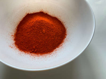 A heap of Chilly powder in a bowl on an isolated white backgroundの写真素材