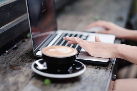 Woman hands typing on laptop keyboard at the office, Woman worker and business concept, Soft focus on vintage wooden table.の写真素材