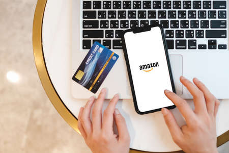Bangkok. Thailand. MAY 16,2020 : Smartphone showing Amazon logo and credit card shopping online in coffee shop. Amazon.com, Inc. American international electronic commerce company.のeditorial素材