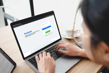Bangkok. Thailand. JUNE 1,2021-Facebook social media app logo on log-in, sign-up registration page on  app screen on laptop computer devices in business person's hand at cafe.のeditorial素材