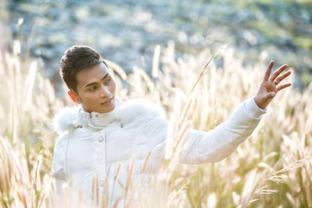 Male model wearing white sweater on the meadow.の写真素材