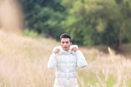 Male model wearing white sweater on the meadow.
