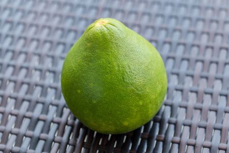 Pomelo on brown plastic rattan weave table. Close up.の写真素材