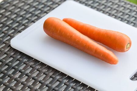 Pair long fresh raw carrot on a plastic cutting board is white color.の写真素材