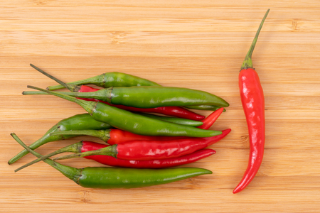 Close up red and green chilli pepper on wood chopping board.の写真素材