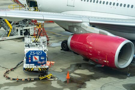 Thailand, Don Mueang International Airport, Bangkok, - 23 July 2018 : Truck with fuel tank on runway. Fuel truck refuel to the passenger plane. Workers Loading Bags Into plane. Oil truck.のeditorial素材