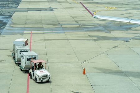 Thailand, Don Mueang International Airport, Bangkok, - 23 July 2018 : Freight trolleys with loaded baggage on the runway.のeditorial素材