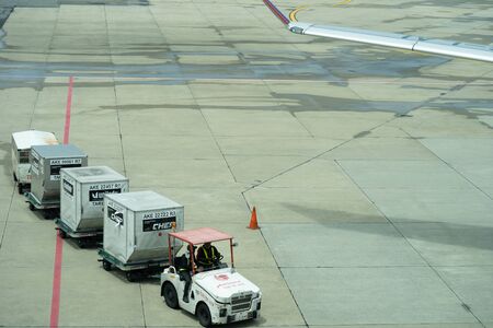 Thailand, Don Mueang International Airport, Bangkok, - 23 July 2018 : Freight trolleys with loaded baggage on the runway.のeditorial素材