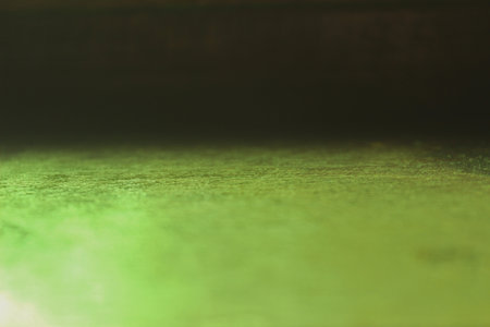 Natural light reflection through green glass onto a wooden surface, creating a captivating interplay of light and shadow. Ideal artistic photo for backgrounds.の写真素材