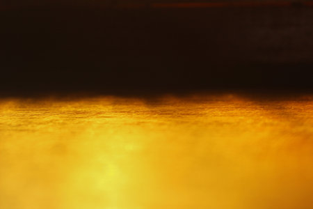 Natural light reflection through yellow glass onto a wooden surface, creating a captivating interplay of light and shadow. Ideal artistic photo for backgrounds.の写真素材