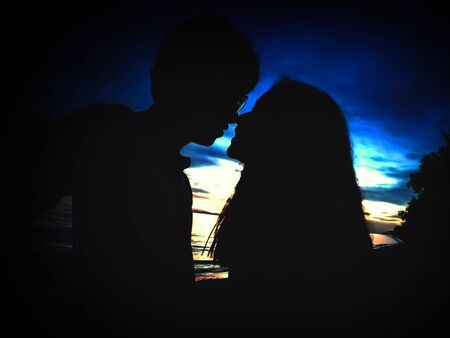 Valentine Concept, Silhouette, Shadow of Sweet Young Couple, Kiss on Different Sky Color Mood, Love Abstract Background.の写真素材