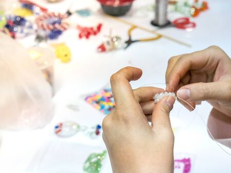 Woman's hand Working hand made weave bead Into various shapes.