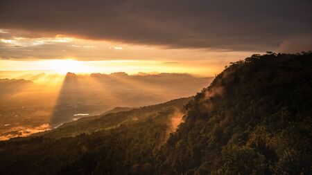Beautiful nature Landscape of sky at Sunrise in the morning, Floating over the vast mountains. The colors of the sky are red and orange. The sun shines through the forest and the mist. Give a Feeling warm, start, hope, new.の写真素材