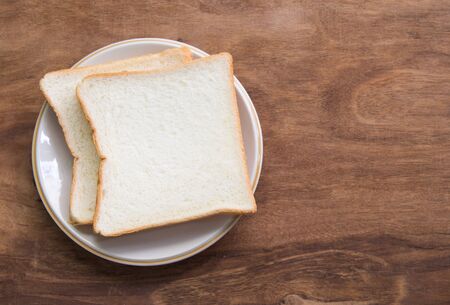 Sliced bread in plate on wooden background.