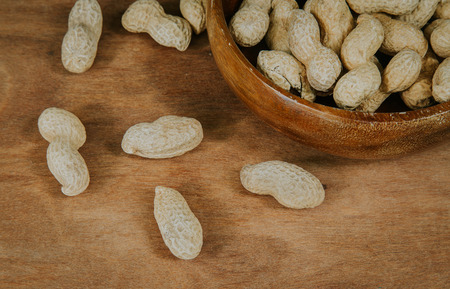 Peanuts in shell in a wooden bowl, selective focus (vintage filter).の写真素材