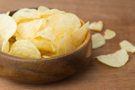 Potato chips in wooden bowl on wooden background.の写真素材