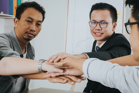 Asian business people putting their hands together. Stack of hands. Unity and teamwork concept.の写真素材