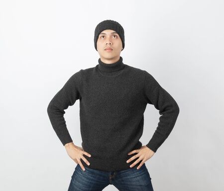 Young handsome asian man wearing grey sweater and beanie thinking an idea while looking up on white background.の写真素材