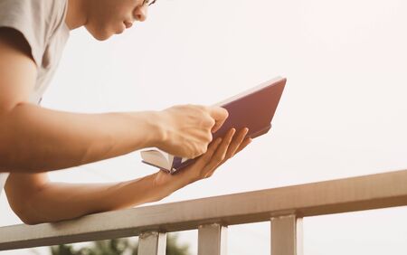 Young man reading book at room balcony in free time from working at home, Knowledge and learning...