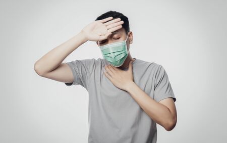 Young Asian Man in hygienic mask suffering sore throat and having flu, 2019-nCoV or coronavirus....