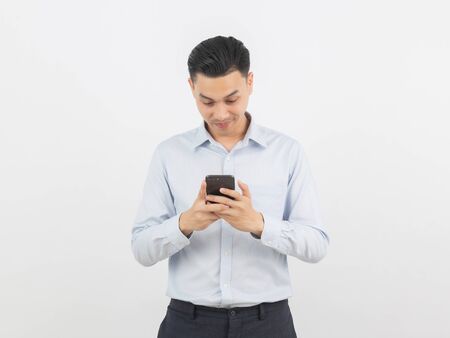 Young handsome asian business man playing smartphone with smiling isolated on white background.の写真素材