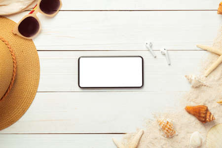 Summer background with blank screen phone and beach accessories - straw hat, sunglasses on white wood table background top view with copy space.の写真素材