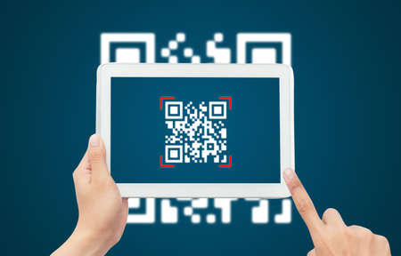 Hand using tablet computer scan Qr code on blue background. Cashless technology and digital money...