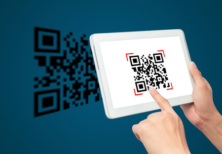 Hand using tablet computer scan Qr code on blue background. Cashless technology and digital money concept.の写真素材