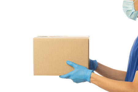 Delivery man hand in medical gloves and wearing mask holding cardboard boxes isolated on white...