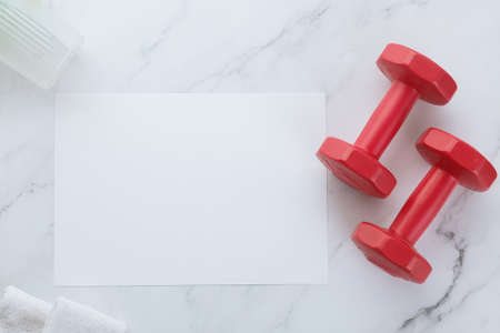 Blank white paper note and dumbells on white marble background. Sport flat lay, Healthy lifestyle and diet concept.の写真素材