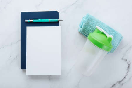 Blank white paper note and fitness equipments on white marble background. Sport flat lay, Healthy lifestyle and diet concept.の写真素材