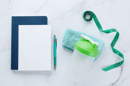 Blank white paper note and fitness equipments on white marble background. Sport flat lay, Healthy lifestyle and diet concept.の写真素材