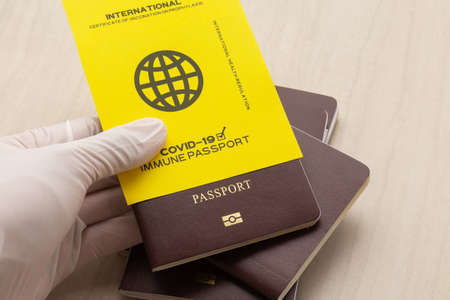 Hand holding vaccine passports as proof that the holder has been vaccinated against Covid-19,...