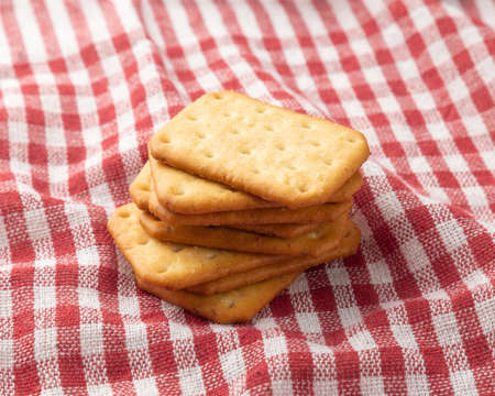 Cracker cookies with tablecloth on white wooden table background.