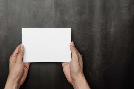 Hand holding Invitation card mockup, blank greeting card template. Flat lay, Minimalist style.の写真素材