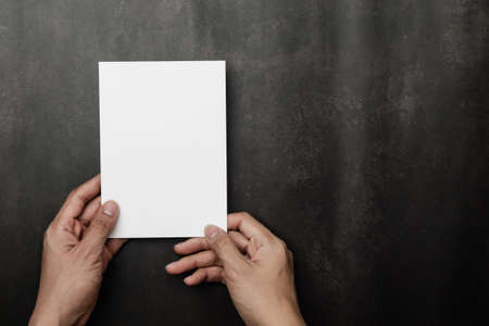 Hand holding invitation card mockup, blank greeting card template. Flat lay, top view.の写真素材