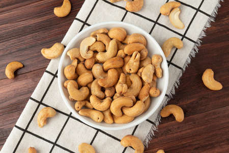 Top view of cashew nuts in white bowl on the table, Flat lay, Healthy snack, Vegetarian food.の写真素材