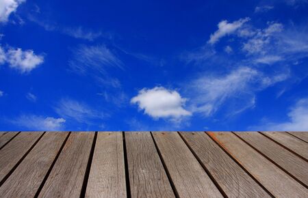 blurred image wood table and abstract clouds in the blue sky backgroundの写真素材