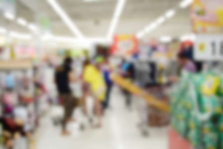 hand hold and touch screen smart phone, on blurred photo of generic supermarket people walking...