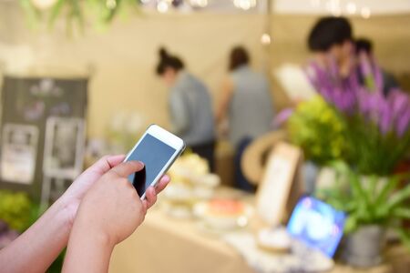 blurred image hand hold and touch screen smart phone and food at night festival with bokeh backgroundの写真素材