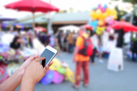 blurred photo and smartphone on people walking street marketの写真素材