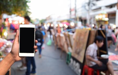 blurred photo and smartphone on people walking street marketの写真素材
