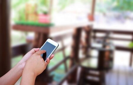 blurred photo and smartphone on woodden chair and table setting on a terrace