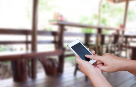 blurred photo and smartphone on woodden chair and table setting on a terraceの写真素材