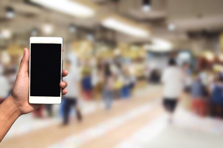 blurred photo and smartphone on food center at shopping mall and people with bokehの写真素材