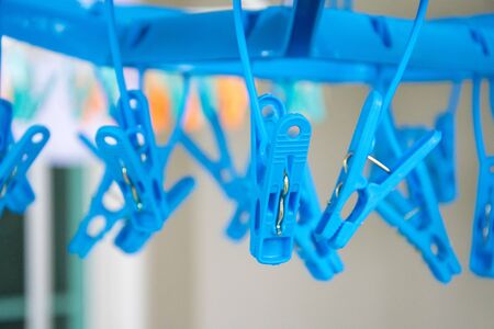 Blue plastic clothespins hanging with hanging pegs on backgroundの写真素材