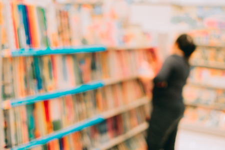 Blurred image abstract people and bookshelves in library as backgroundの写真素材